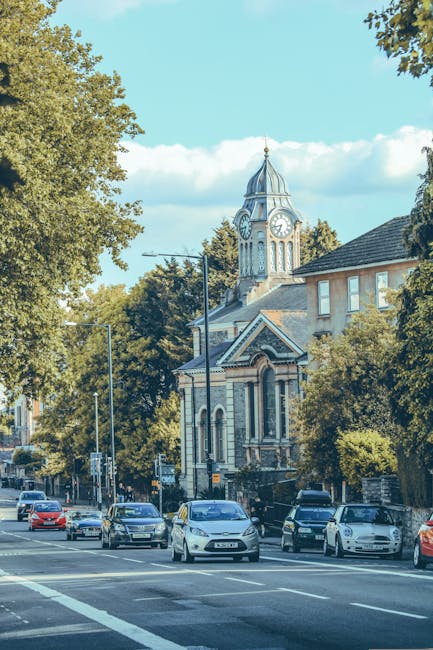 The image shows a parking area in Kingston with several parked cars lined up along the curb, adjacent to a row of historic brick and stucco residential buildings featuring multiple stories, bay window